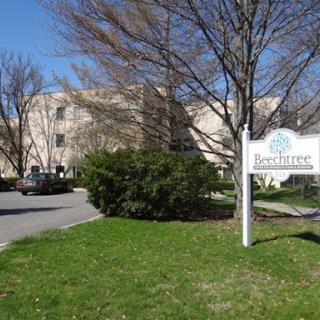 A serene view of a building with a sign, surrounded by lush grass and trees on a clear day.