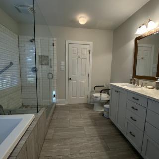 A modern bathroom interior featuring a large mirror, sink, bathtub, and shower area.