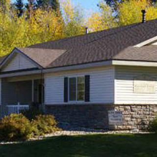 A suburban single-story house surrounded by autumn trees.