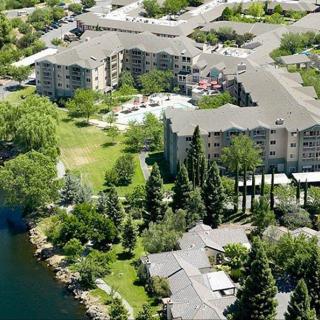 Aerial view of residential buildings surrounded by lush greenery and a nearby river.