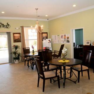 A cozy dining area with multiple tables and chairs, decorated with plants and wall art.