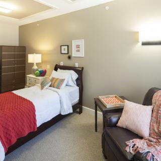 A cozy, modern bedroom with a neatly made bed, stylish furniture, and warm lighting.