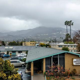 A scenic view of mountains under a cloudy sky, with urban buildings in the foreground.