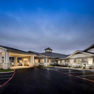 A well-lit building exterior with a parking lot during the evening.