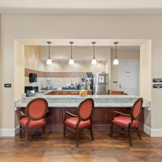 A modern kitchen with a countertop, red cushioned chairs, and pendant lighting.