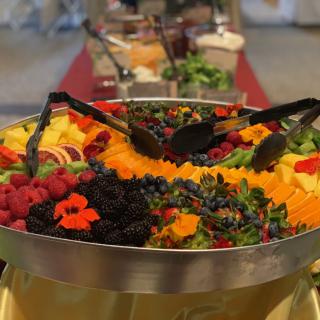 A vibrant fruit platter featuring an assortment of berries and sliced fruits at a buffet.