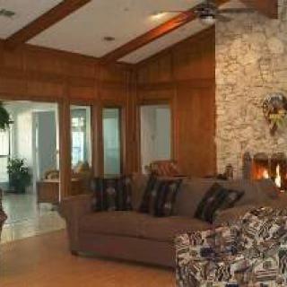 A cozy living room featuring a large sofa, stone fireplace, and wooden ceiling beams.
