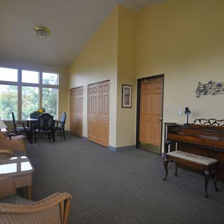 A spacious room with a piano, seating area, and large windows providing natural light.