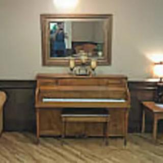 A cozy room with a piano, mirror, and guitar.
