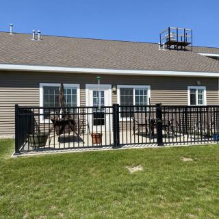 A backyard with a fenced patio area and lawn chairs on a sunny day.