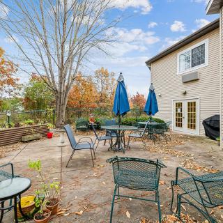 A backyard patio with tables, chairs, and umbrellas set against an autumn landscape.