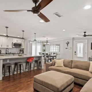 A modern open-concept living room and kitchen area featuring neutral-toned furniture and hardwood flooring.