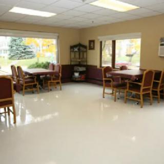 A bright dining area with tables and chairs, featuring large windows.