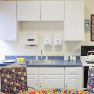 A kitchen area with white cabinets, a sink, and toys on the table.