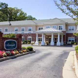 A well-maintained building entrance with a driveway and landscaped garden.