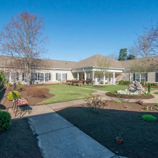 A spacious house with a well-maintained garden and pathway under a clear blue sky.