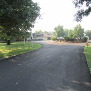 A peaceful, curving driveway surrounded by trees in a suburban setting.
