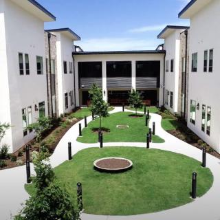 A modern courtyard with well-maintained landscaping and walkways, surrounded by white buildings.