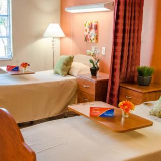 A cozy bedroom with twin beds, decorated with flowers and a warm lamp.