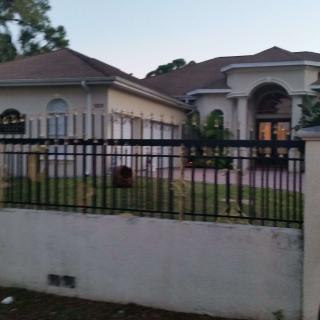 A view of a large residential house with a fenced yard.