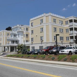 A residential apartment building with parked cars along the adjacent road.