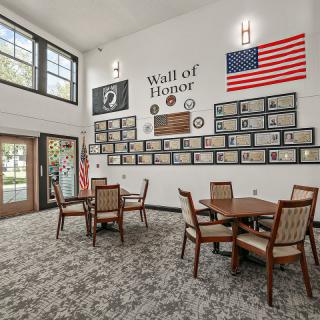 A room with a Wall of Honor featuring framed photos, American flags, and seating area.