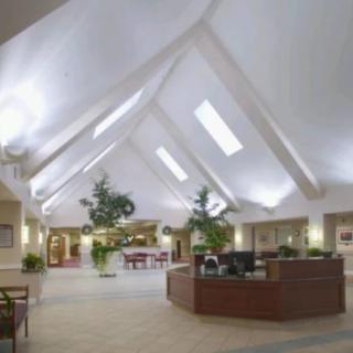 A spacious lobby with modern design elements, featuring a reception desk and skylights.