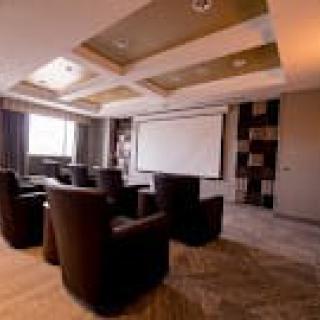 A modern conference room equipped with comfortable seating and a projector screen.
