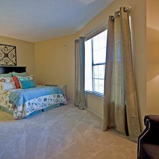 A cozy bedroom with a colorful bedspread and large window.