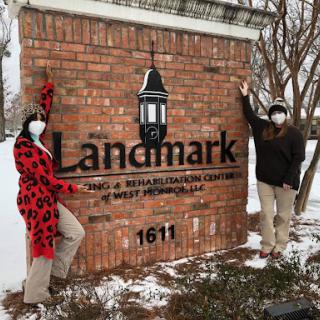 Visitors posing by the Landmark sign in a snowy setting.