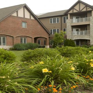A well-maintained apartment building with lush landscaping and blooming flowers in the foreground.