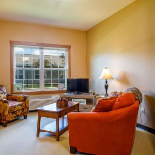 Cozy living room with a sofa, armchair, coffee table, and television near a large window.