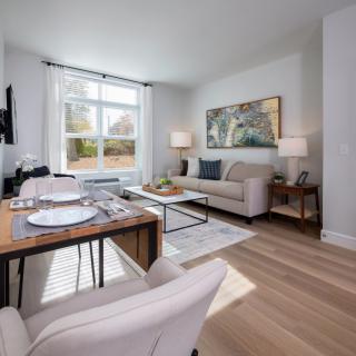 A modern living room with a dining area, featuring comfortable seating and ample natural light.