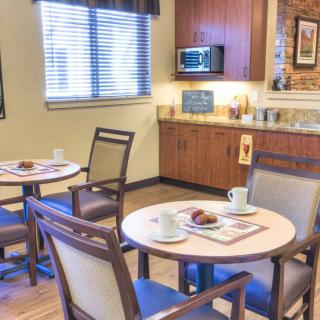 A cozy dining area with a kitchenette and several round tables set for meals.