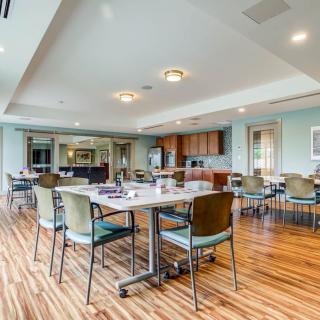 A modern and spacious dining area with wooden flooring and well-arranged tables and chairs.