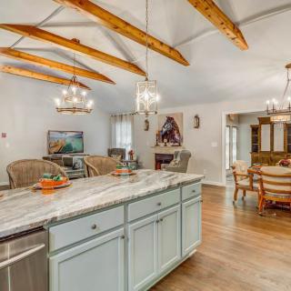 A spacious kitchen and dining area featuring wooden beams, elegant chandeliers, and a marble countertop island.