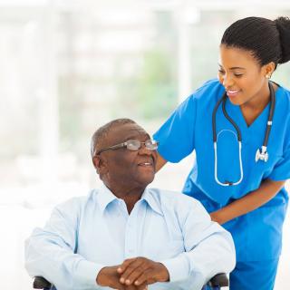 A nurse providing care and support to an elderly patient in a wheelchair.