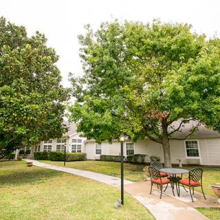 A serene outdoor area with a pathway, surrounded by trees and residential buildings.