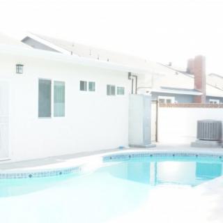 A backyard with a swimming pool and a house in the background.