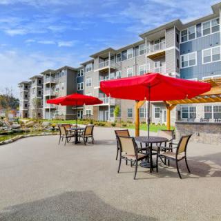 Modern apartment complex with outdoor patio seating and red umbrellas.