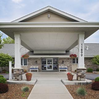 The entrance of a building with a covered walkway and neatly arranged landscaping.