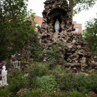 A serene outdoor grotto featuring statues and lush greenery.