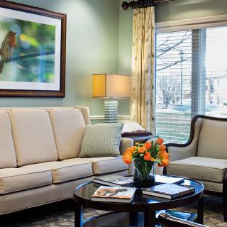 A cozy living room with a beige sofa, elegant chair, and vibrant flowers on a coffee table.