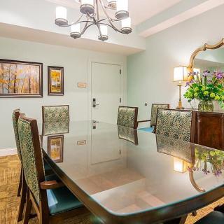 A well-decorated dining room featuring a polished table, elegant chairs, a modern chandelier, and tasteful artwork.