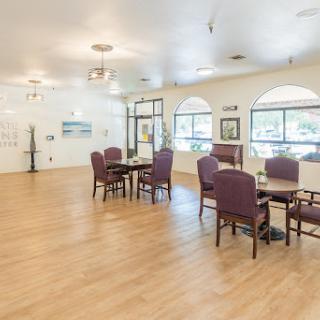 A spacious and bright dining area with purple chairs and tables, featuring large windows.