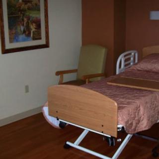 An empty hospital room with a bed and chair.
