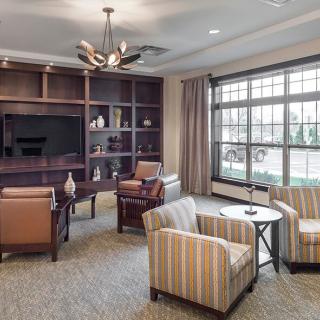 A cozy living room with comfortable seating, a large window, and bookshelves.