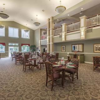 A spacious and elegantly decorated dining area with tables and chairs under a high ceiling.