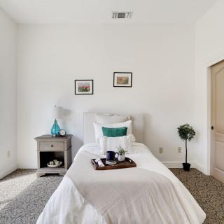 A minimalist bedroom with a single bed and nightstand, featuring clean white walls and simple decor.