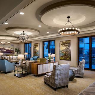 A luxurious living room featuring elegant chandeliers, modern furniture, and large windows overlooking a scenic view.